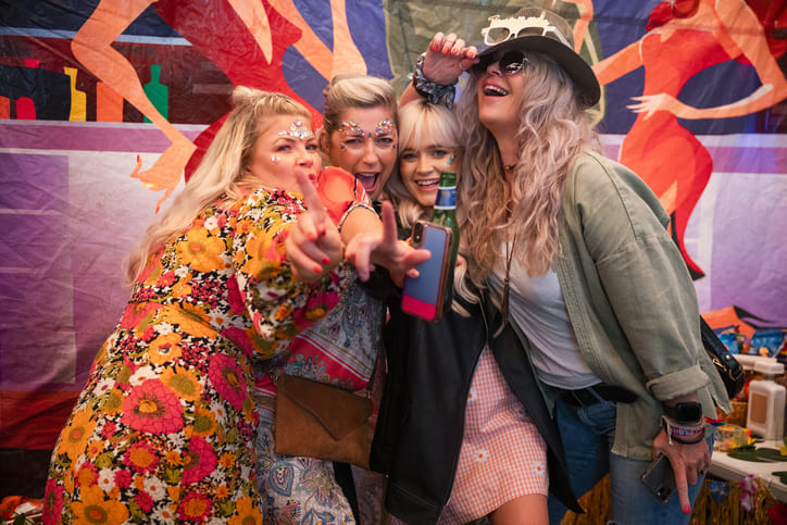 4 Frauen die sich für Fasching in Kostüme geschmissen haben und sehr glücklich in die Kamera schauen.