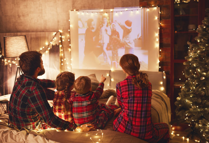 Familie schaut Weihnachtsfilme. Auf einer großen Leinwand in weihnachtlicher Stimmung