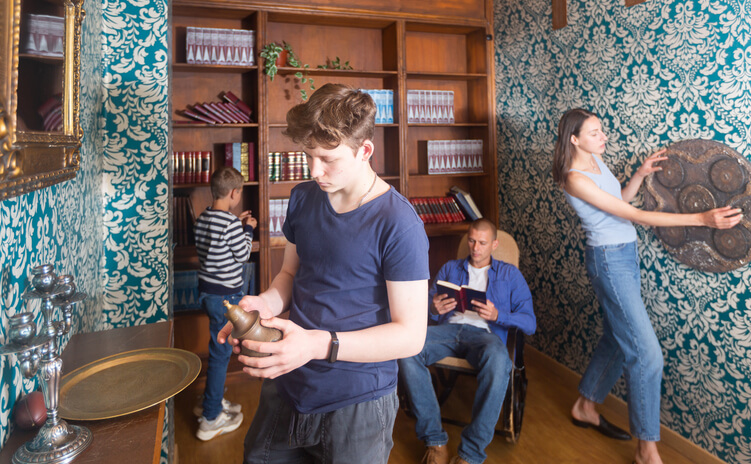 Familie in einem Escape Room. Vier Personen schauen sich interessiert im Raum um.