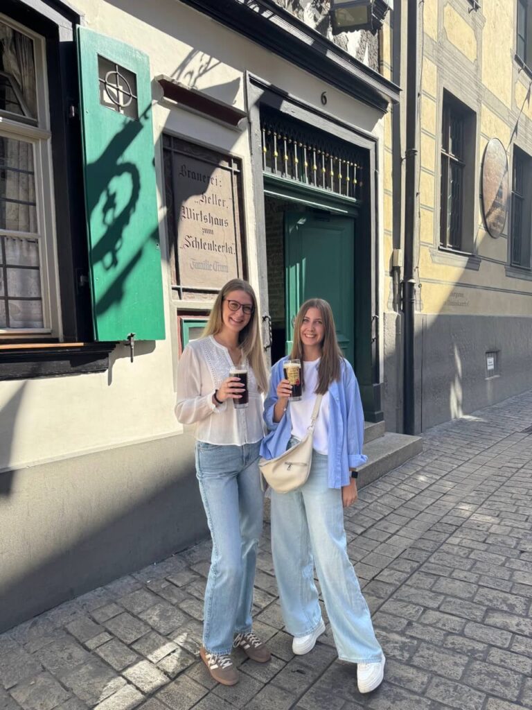 Events in Bamberg. Zwei Frauen in der Sandstraße vor einer Brauerei mit einem Rauchbier in der Hand. 