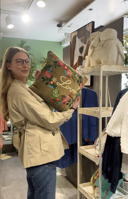 Bild von einer City Blog Mitarbeiterin die ein buntes frühlingshaftes Kissen hochhält.