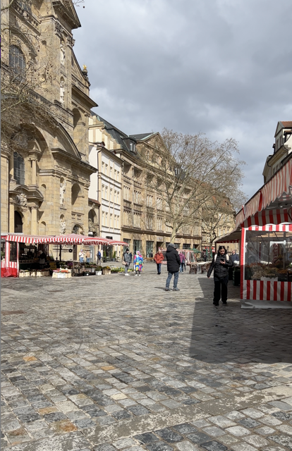 Blick auf die Kulisse des Bamberger Wochenmarkts. Zu sehen ist ein Blumenstand und im Hintergrund die Kirche am Grünen Markt.