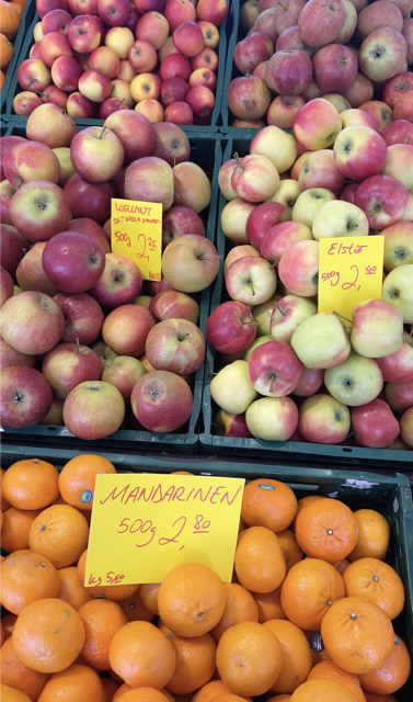 Bild vom Obstangebot eines Markstandes auf dem Wochenmarkt. Im Vordergrund sind Mandarinen zu sehen, im Hintergrund verschiedene Apfelsorten.