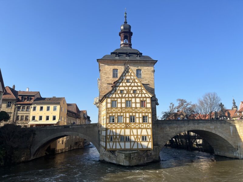 Der Frühling in Bamberg erwacht. Zu sehen ist das alte Rathaus in Bamberg und die untere Brücke in sonnigem Licht.