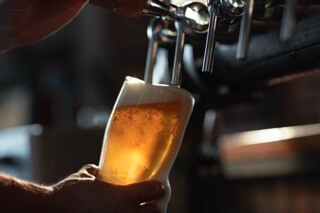 Ein Bier wird gerade bei einem der Bockbieranstiche frisch gezapft. Bier in nahaufnahme und Zapfhahn obern drüber.